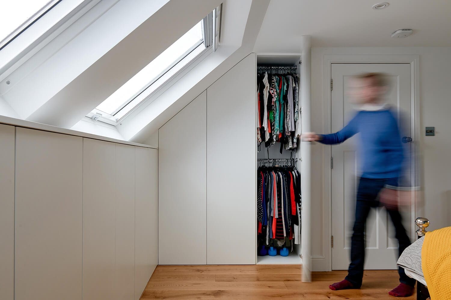 man opening white wardrobe door in loft bedroom