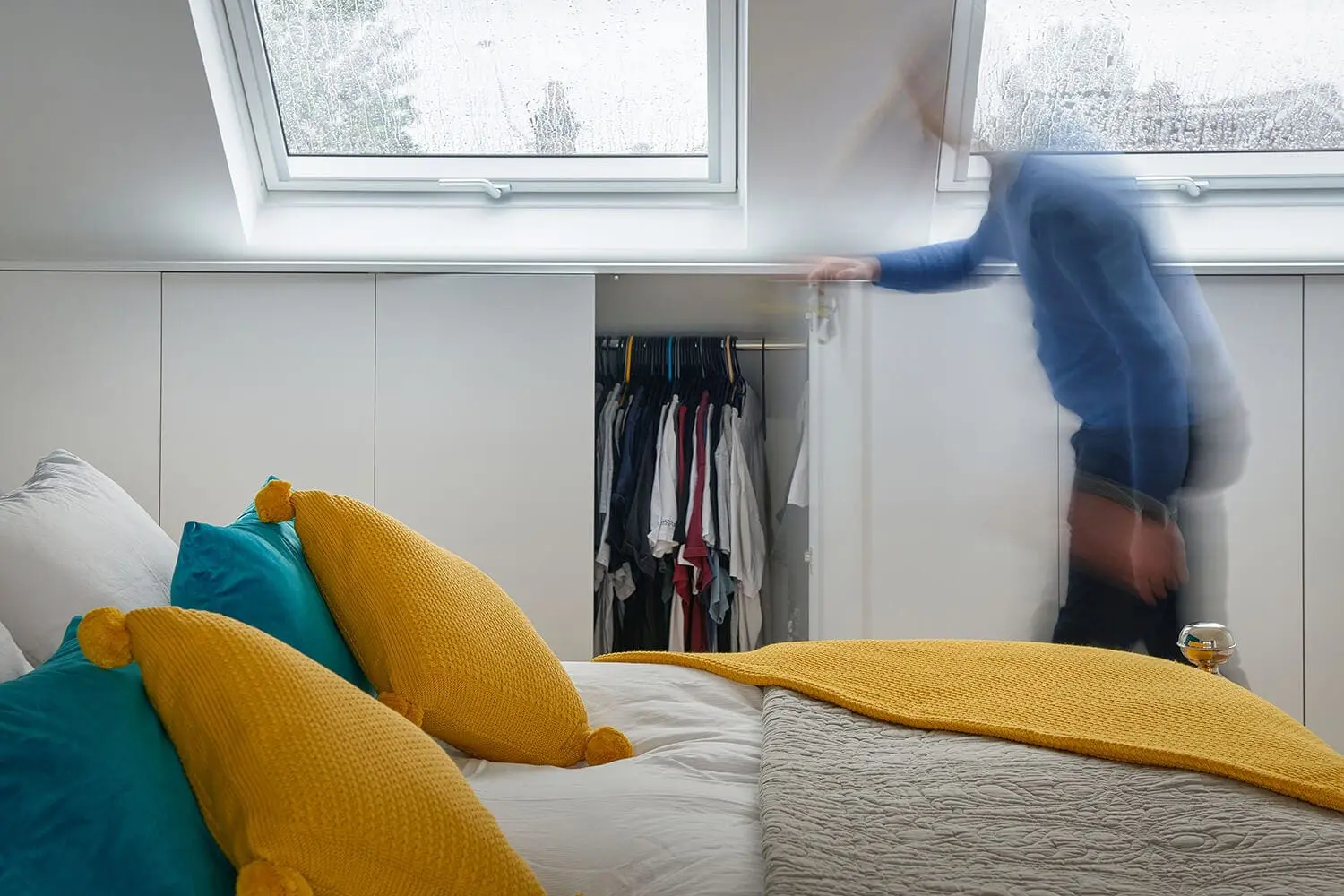 man opening under-eaves bespoke hanging storage on loft conversion